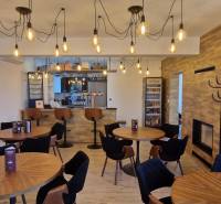 Vendéglátóhelyek fa mintázatú padlóval és függő lámpákkal.