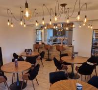 Vendéglátóhely belső terei fa dekorációjú padlóval és izzólámpás világítással.