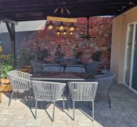 Új Dedinán található kültéri vendéglátóhelyeken rattan székek és téglafal van.