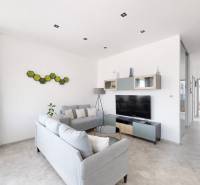 Nappali egy háromszobás lakásban modern bútorokkal és televízióval, dekoráció a falon.