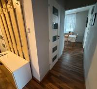 Folyosó egy 3 szobás lakásban, fa mintázatú padlóval és asztallal az ablaknál.