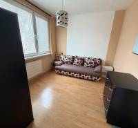 Szoba kanapéval, komóddal és fa dekorációjú padlóval egy háromszobás lakásban.