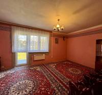 Nappali egy családi házban piros szőnyeggel, egyszerű függönyökkel és világítással.