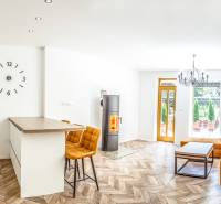 Világos nyaraló apartman konyhával, narancssárga kanapéval és fa mintázatú padlóval.