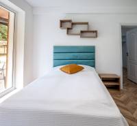 Egyágyas ágy a nyaraló apartmanban fa hatású padlóval és nagy ablakkal.