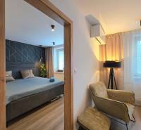 Kétszobás lakás fa dekor padlóval tartalmaz egy hálószobát, egy széket és egy lámpát.