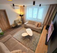 Nappali egy kétszobás lakásban kényelmes kanapéval, dohányzóasztalokkal és fa dekorációjú padlóval.