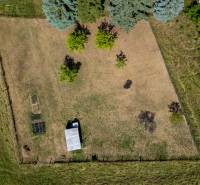 Légi felvétel egy lakóterületnek szánt telekről Banská Belában, füves területtel és fákkal.