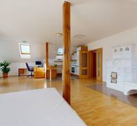 Családi ház tetőtéri belső tere cserépkályhával, dolgozósarokkal és fa dekorációjú padlóval.