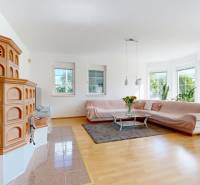 Nappali egy családi házban cserépkályhával, kanapéval és fa dekoros padlóval.