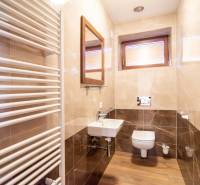 Családi ház fürdőszobája fa dekor padlóval, mosdóval és fűtőtesttel.