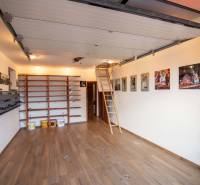 Garázs a családi házban polcokkal, fa dekor padlóval és kihúzható létrával.