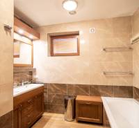 Fürdőszoba családi házban káddal, mosdóval, zuhanyzóval és fa dekoros padlóval.