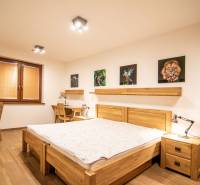 Hálószoba családi házban, fa mintázatú padlóval, képekkel és íróasztalokkal.