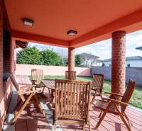 A Krajná utcai családi ház terasza Stomfán, fa bútorokkal és téglafalakkal.