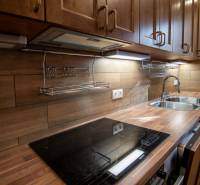 Családi ház konyhája fa dekoros padlóval és fából készült konyhabútorral.