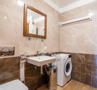 Fürdőszoba családi házban mosógéppel, mosdóval és fa mintázatú padlóval.