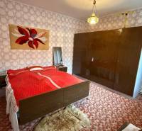 Hálószoba családi házban szőnyeggel, mintás tapétával és nagy szekrénnyel.