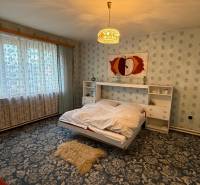 Hálószoba családi házban virágos szőnyeggel és nagy ablakkal.