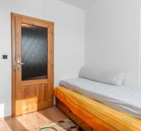 Egyszerű szoba egy négy hálószobás lakásban, ággyal és fa dekorációjú padlóval.