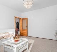 Világos szoba virágmintás ágyneművel, asztallal és csillárral egy 4 szobás lakásban.