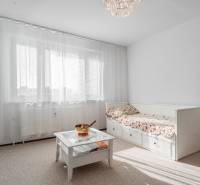 Világos szoba egy 4 szobás lakásban kanapéval, asztallal és függönyökkel az ablakon.