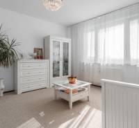 Világos szoba üvegvitrinnel, fehér bútorokkal és növényekkel egy 4 szobás lakásban.