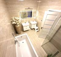 Fürdőszoba családi házban káddal, mosdóval, virágkompozícióval és nagy tükörrel.