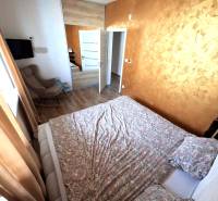 Hálószoba családi házban, fa dekoros padlóval, barna függönyökkel és mintás ággyal.