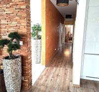 Családi ház belső tere dekoratív fallal, fa mintázatú padlóval és modern kiegészítőkkel.