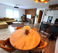 Nappali egy családi házban kanapéval, étkezőasztallal és fa mintázatú padlóval.