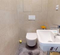 Kompakt fürdőszoba világos csempékkel, mosdóval és WC-vel egy háromszobás lakásban.