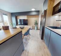 Konyha egy háromszobás lakásban fa dekor padlóval és étkezőasztallal.