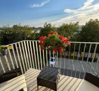 Erkély egy háromszobás lakásban kilátással a Odevná utcára Trencsénben, virágokkal és kerti bútorokkal.