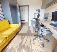 Dolgozószoba egy háromszobás lakásban fa dekor padlóval és sárga kanapéval.