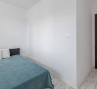 Hálószoba egy kétszobás lakásban ággyal, párnákkal és faajtókkal.