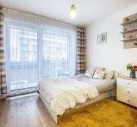 Világos egyszobás lakás ággyal, szőnyeggel és fa dekor padlóval.