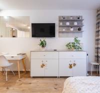 1 szobás lakás belső tere fehér bútorokkal és fa dekorációjú padlóval.