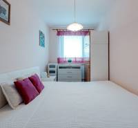 Hálószoba világos bútorokkal és dekoratív párnákkal egy 4 szobás lakásban.