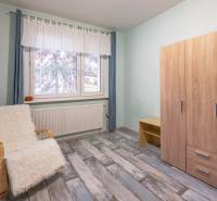 Szoba egy négy szobás lakásban, szekrénnyel, székkel és fa dekorációjú padlóval.