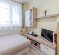 Egy 4 szobás lakás belső tere kanapéval, televízióval és fa dekorációjú bútorokkal.