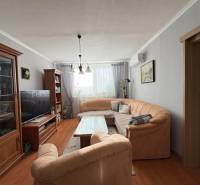 Nappali kényelmes kanapéval, fa dekorációjú padlóval és kellemes világítással egy háromszobás lakásban.