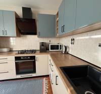 Konyhaszekrény a háromszobás lakásban fa dekor padlóval és háztartási gépekkel.