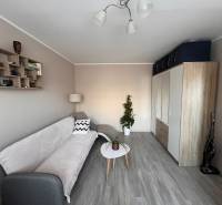 Világos nappali háromszobás lakásban, fa dekoros padlóval és kényelmes kanapéval.