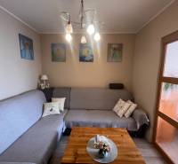 Nappali egy háromszobás lakásban kanapéval, képekkel és fa dekorációjú padlóval.