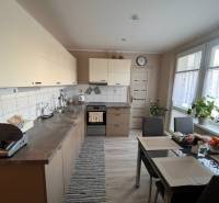 Konyha egy háromszobás lakásban asztallal, készülékekkel és növényekkel.