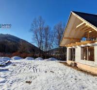 Téli házépítés a Mýte pod Ďumbierom utcán havas tájban.