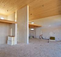 Egy magas mennyezetű házikó belseje, nyersen kialakított falak és finom fa dekorációk.