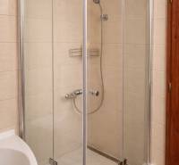 Zuhanyzó egy háromszobás lakásban, egyszerű dizájnnal és világos csempékkel.