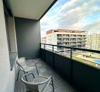 Erkély két székkel és fa dekoros csempékkel, kilátás az épületekre.